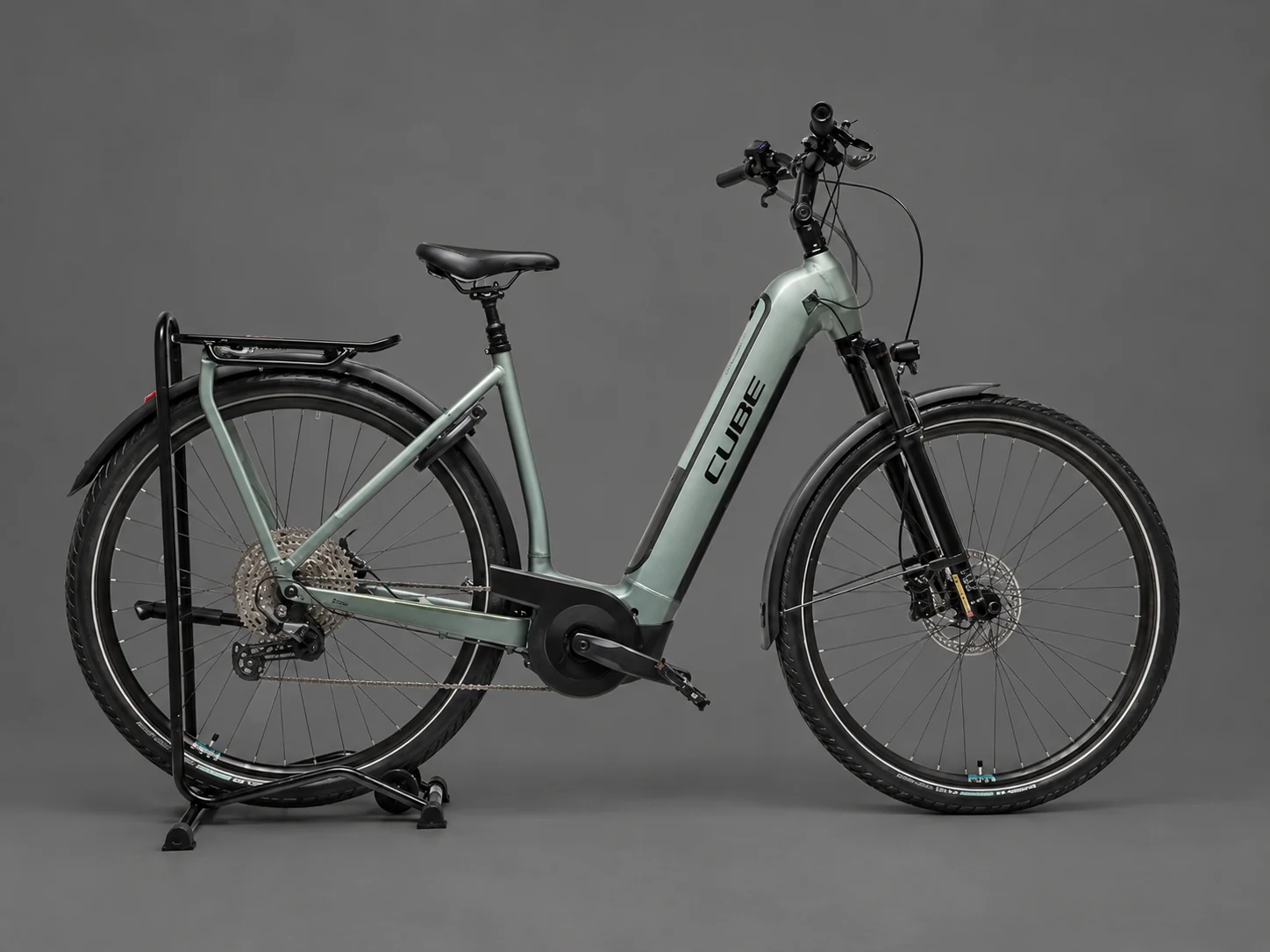 Graugrünes Trekking-E-Bike mit Gepäckträger in einer Studioaufnahme