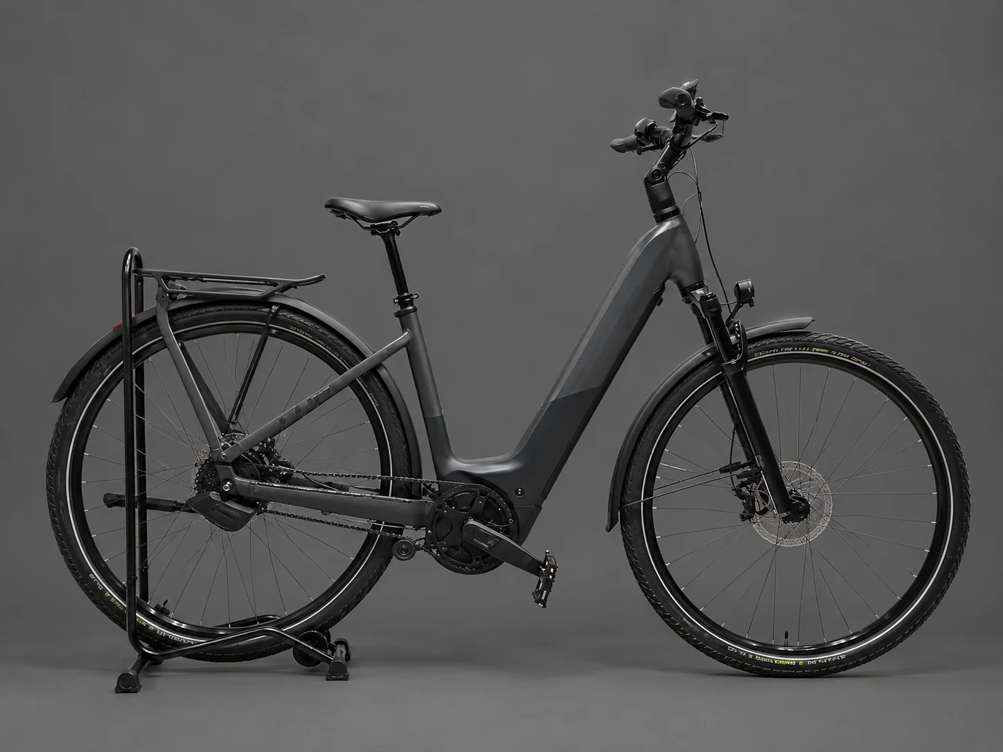 Graues Trekking-E-Bike mit Gepäckträger in einer Studioaufnahme